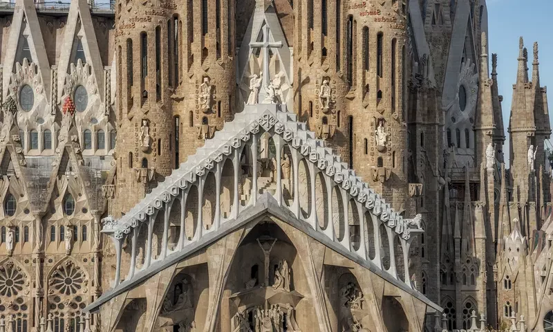 Bazylika Sagrada Familia przedstawiona w całej okazałości od strony wejścia, z tyłu widać żurawie używane przy budowie. / sagradafamilia.org