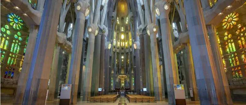 Wnętrze Sagrady Famílii, widać kolorowe witraże, przez które wpada światło oraz całą orginalną strukturę budowli. / sagradafamilia.org