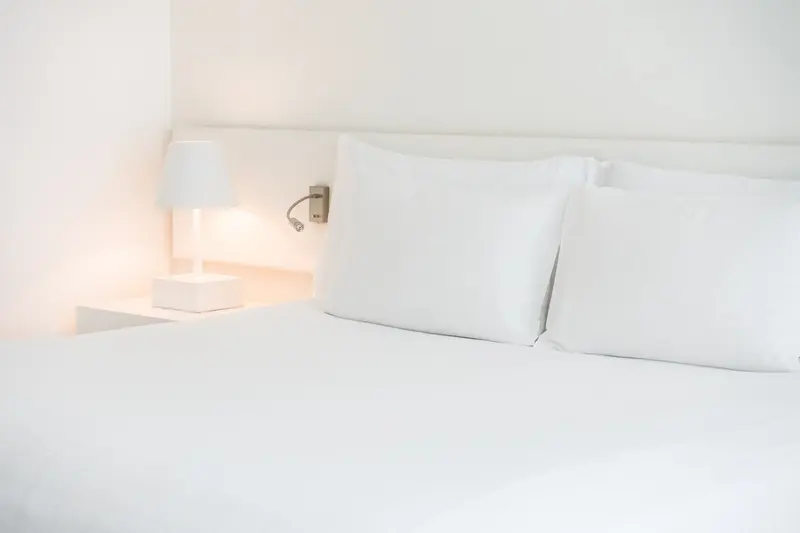 Pościelone łóżko z białymi poszewkami / fot. lifeforstock freepik.com