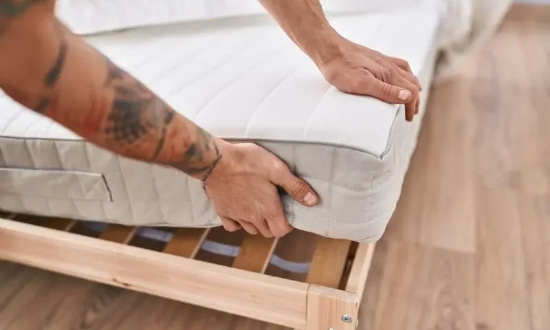 Mężczyzna kładzie materac na stelaż łóżka / fot. krakenimages.com freepik.com