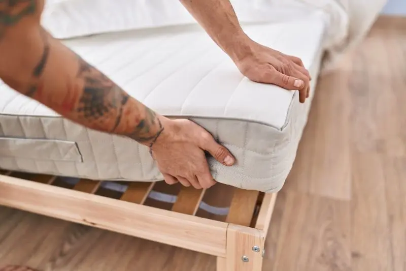 Mężczyzna kładzie materac na stelaż łóżka / fot. krakenimages.com freepik.com