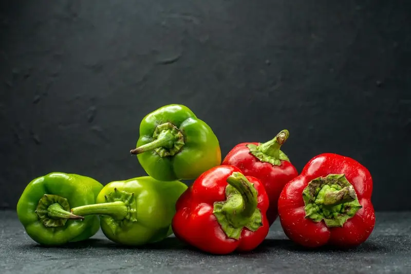Zielona i czerwona papryka na stole / fot. KamranAydinov freepik.com